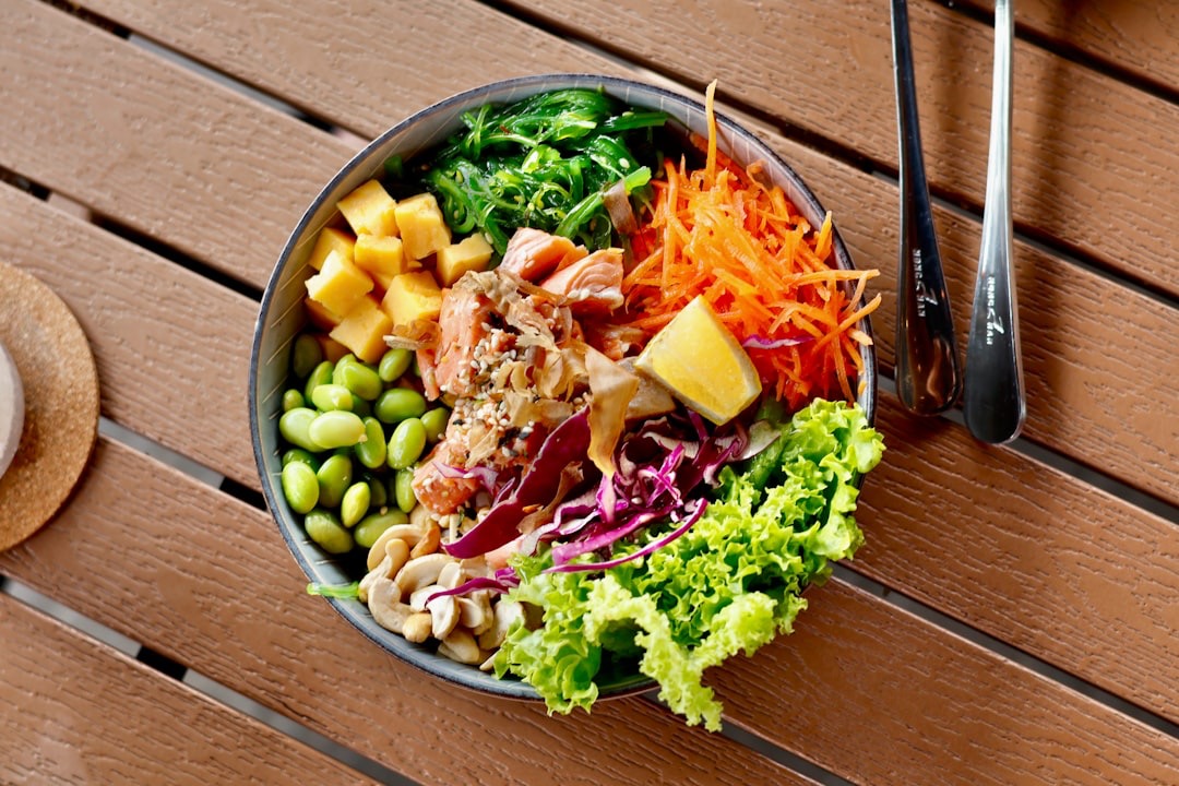 Fresh poke bowl with salmon and mango on an outdoor table.